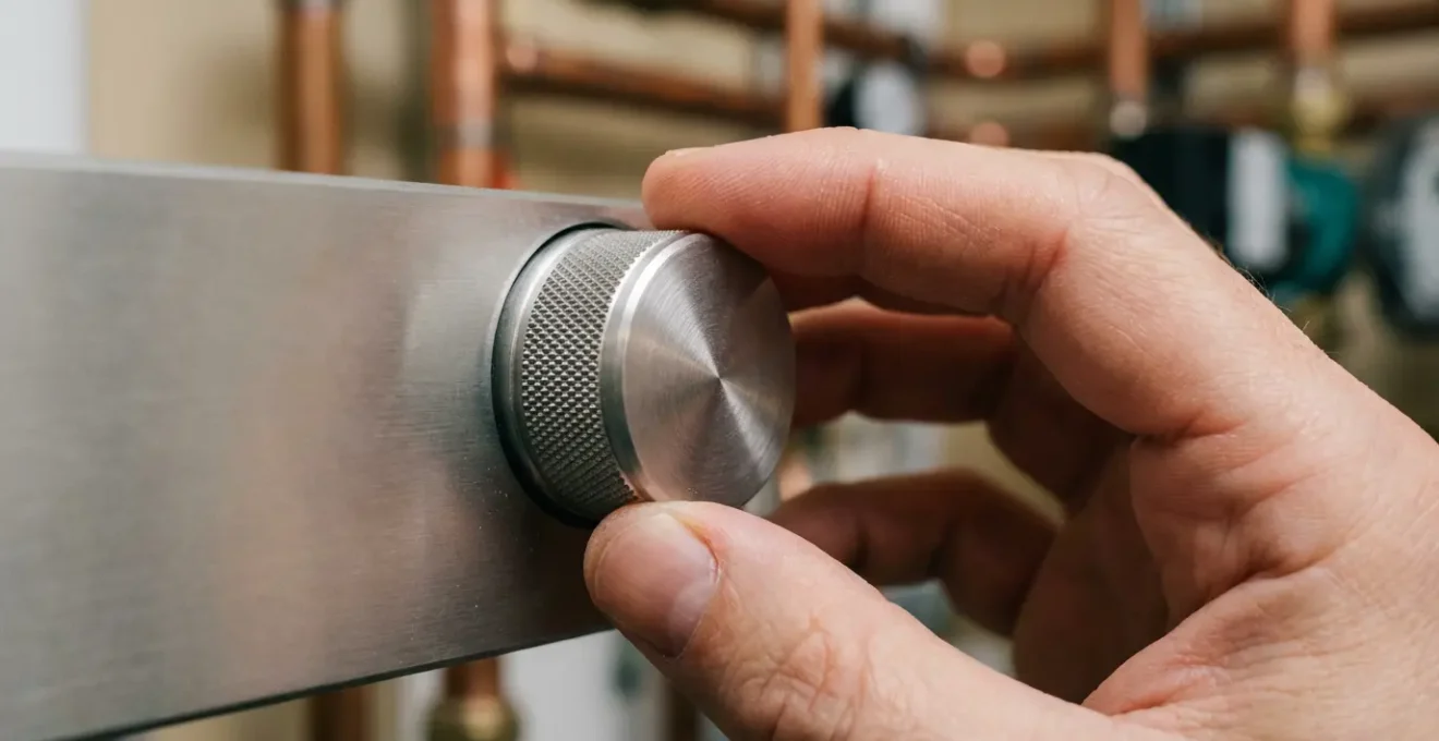 Main ajustant un thermostat de chaudière moderne avec affichage numérique